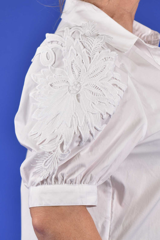 Close-up of embroidered floral appliqué design on puff sleeve blouse