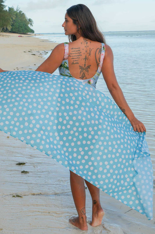 Woman holding a blue polka dot sarong on a beach