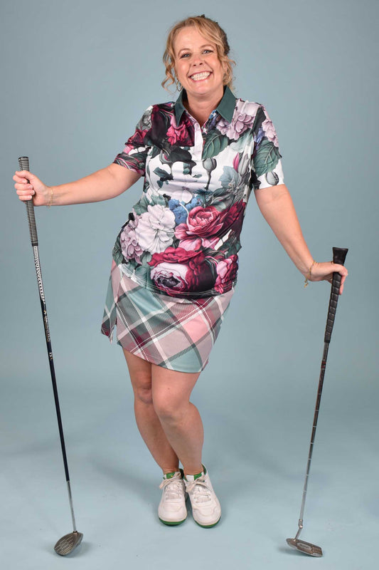 Woman in a floral and plaid setholding golf clubs on a blue background