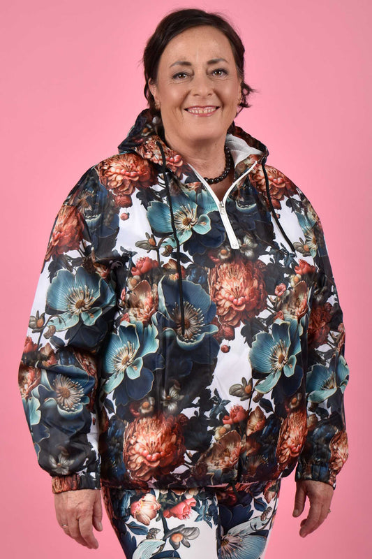 A person wearing a blue floral windbreaker jacket with a hood.