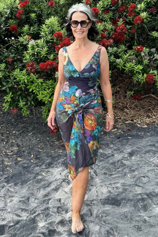 A woman standing on a beach wearing a vintage navy swim scarf wrap with a colorful floral design.