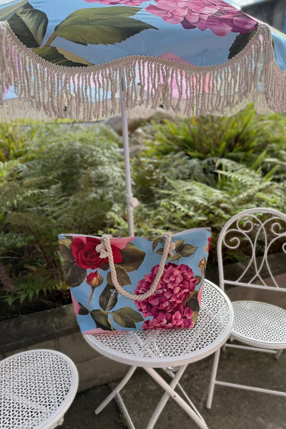 Floral-patterned bag and umbrella on a table with garden chairs in the background