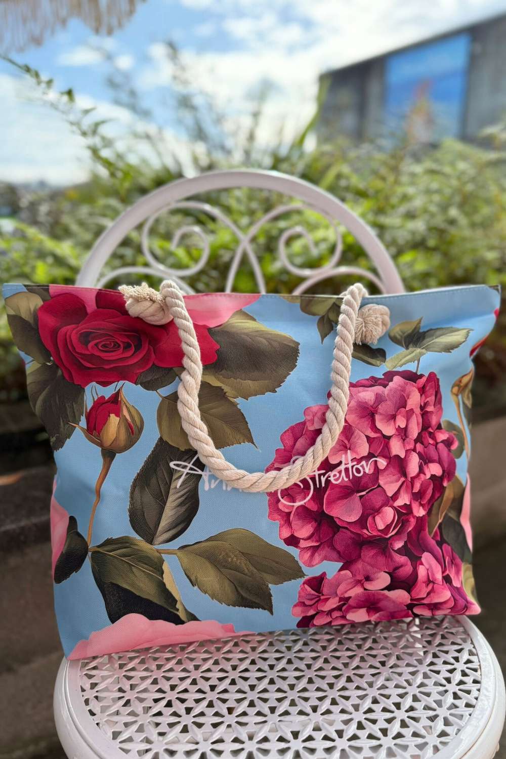 Floral-patterned bag with pink accents on a white chair outdoors