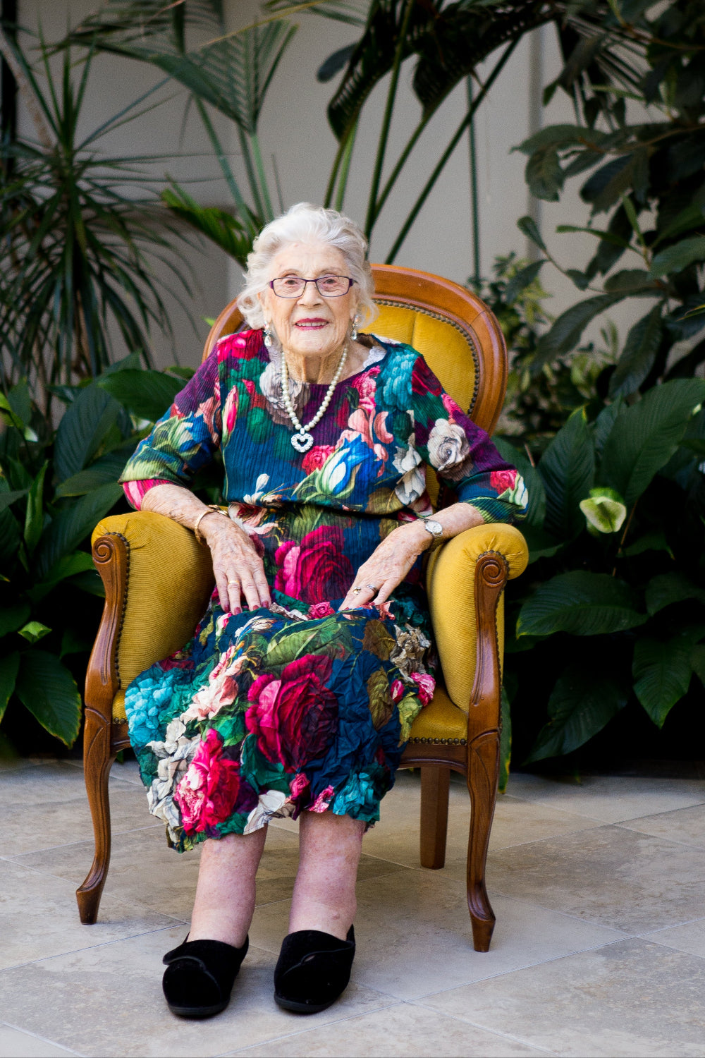Woman in a colorful dress sitting in a chair surrounded by plants