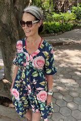 Woman wearing a floral dress standing outdoors on a sunny day.