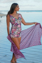 Woman in a floral swimsuit with a matching polka dot cover-up on a beach.