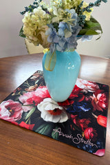 Floral arrangement in a blue vase on a floral placemat with 'Annah Stretton' branding.
