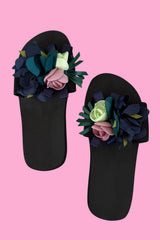 Black sandals with floral decorations on a pink background