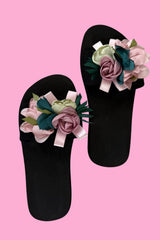 Black flip-flops with floral decorations on a pink background