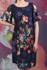Close-up of the fabric on the Pleat Me Dahlia dress showing a navy blue background with bright multi-coloured dahlia flowers