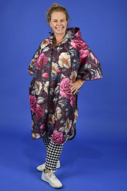 Woman wearing Annah Stretton Jungle Mulberry floral rain poncho – waterproof festival poncho