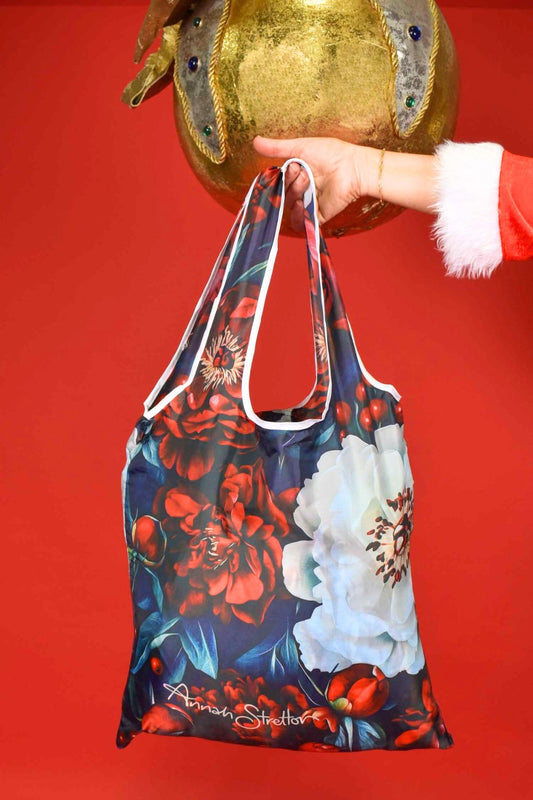 Floral-patterned bag held by a hand against a red background