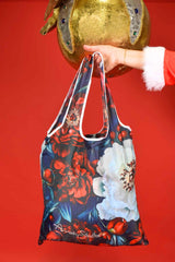 Floral-patterned bag held by a hand against a red background