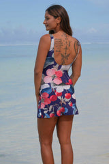 Layla Skirt Bather Blossom Party Annah Stretton – back view showing navy floral skirted swimsuit with cherry, strawberry, and pink floral Blossom Party print, wide straps, and flared skirt hem, beach setting