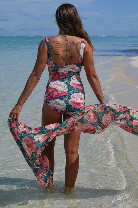 Erika Bather Vintage Peonies Annah Stretton – back view showing low open back, wide straps, and large-scale pink and coral peony floral print on deep teal, styled with matching wrap at beach