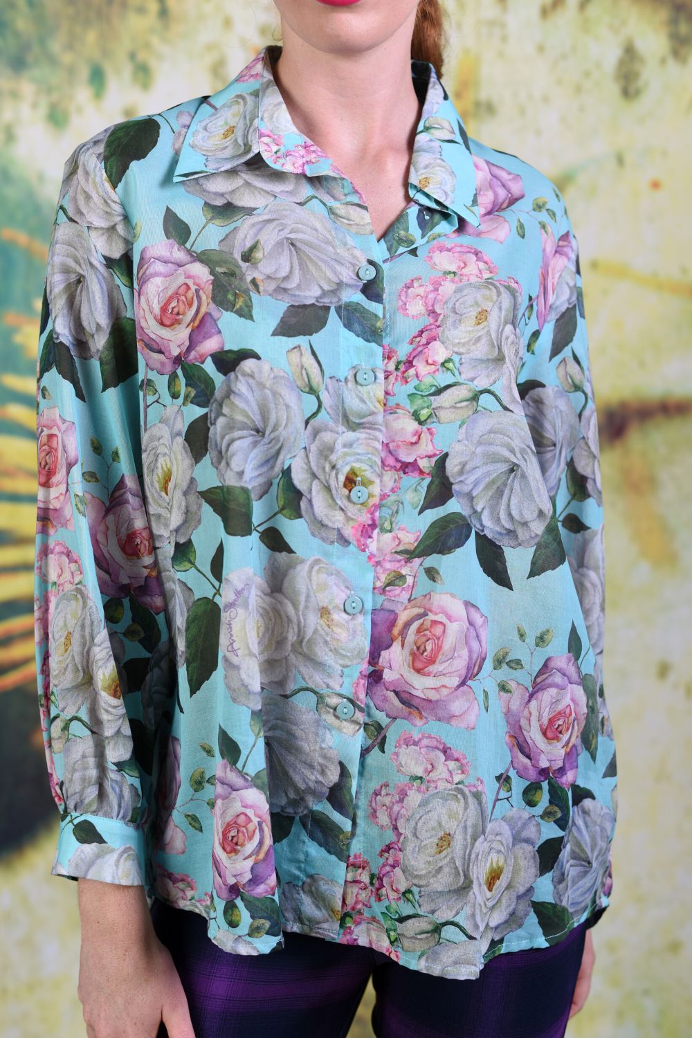 Close-up of fabric of the Annah Stretton Elsie Shirt showing a pink and white rose pattern atop a mint blue background
