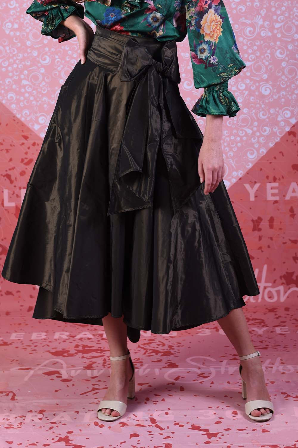 Miriam Max skirt in gold showing the asymmetrical hemline and large statement bow