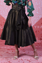 Miriam Max skirt in gold showing the asymmetrical hemline and large statement bow